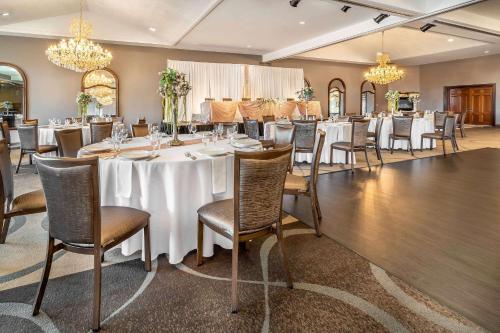 uma sala de jantar com mesas e cadeiras brancas e lustres em Riverview Inn & Suites, Ascend Hotel Collection em Rockford