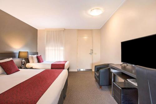 a hotel room with two beds and a flat screen tv at Comfort Inn Western in Warrnambool