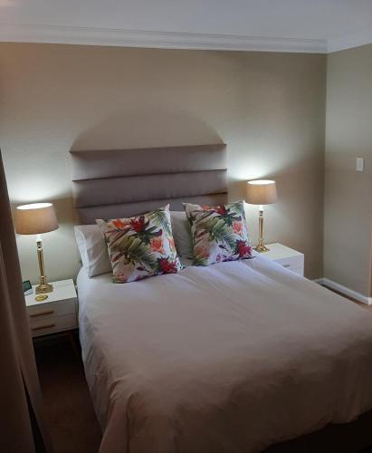 a bedroom with a large white bed with two lamps at Little Elm Cottage in Cape Town