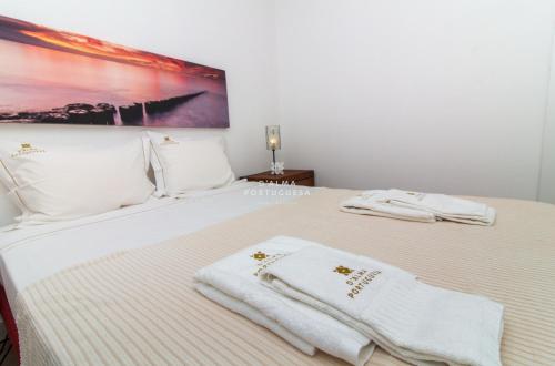 una camera da letto con un letto con asciugamani bianchi sopra di Apartment Aveiros Beach- D´Alma Amado a Vale de Pedras