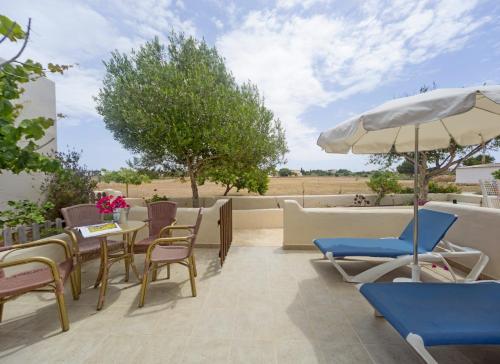 un patio con mesas, sillas y una sombrilla en Es Garrovers - Formentera Break, en Sant Ferran de Ses Roques