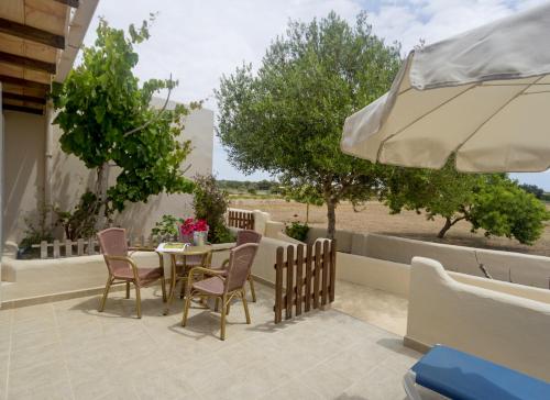 een patio met een tafel en stoelen en een parasol bij Es Garrovers - Formentera Break in Sant Ferran de Ses Roques