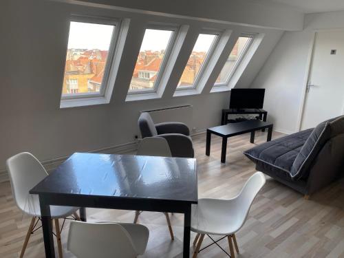 un salon avec une table, des chaises et des fenêtres dans l'établissement Appartement 300m Plage, à Dunkerque