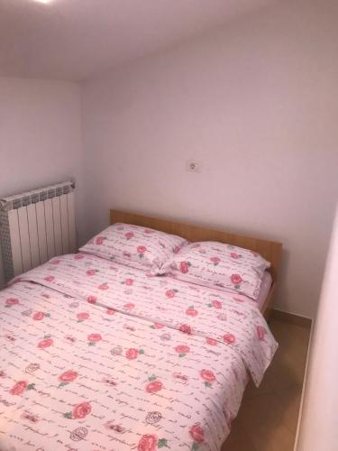 1 Schlafzimmer mit einem Bett mit rosa geblümter Bettdecke in der Unterkunft Apartman Voch in Zambratija