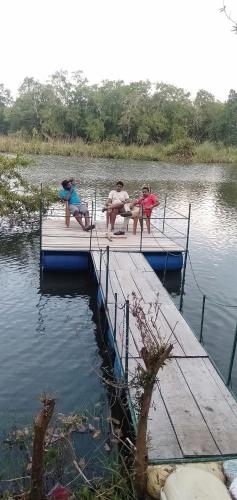 a group of people sitting on a dock in the water at Wilpattu Green Cabin in Achchamulai