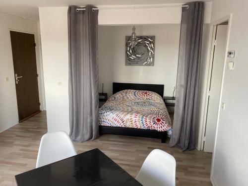 een slaapkamer met een bed en een tafel en stoelen bij Appartement 300m Plage in Duinkerke