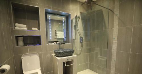ein Bad mit einer Dusche mit einem Waschbecken und einer Glasdusche in der Unterkunft The Old Hall Hotel in Coventry