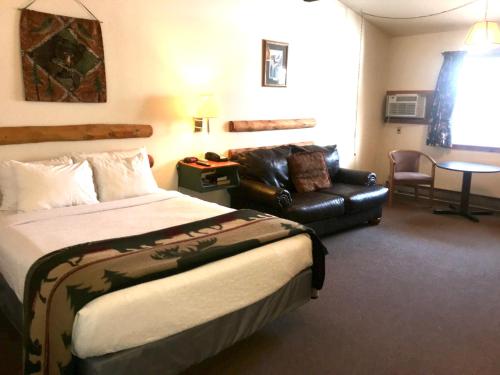 ein Hotelzimmer mit einem Bett und einem Ledersofa in der Unterkunft Hiawatha Lodge Inn in Eagle River