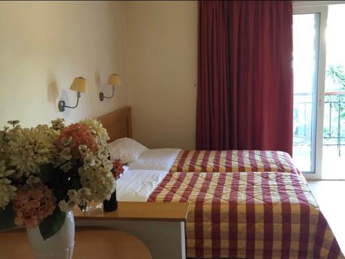 a bedroom with a bed and a table with a vase of flowers at PHILOXENIA PENSION in Ermioni