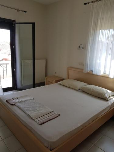 a bedroom with a large bed with a window at Lemon Flowers Apartments in Nea Skioni