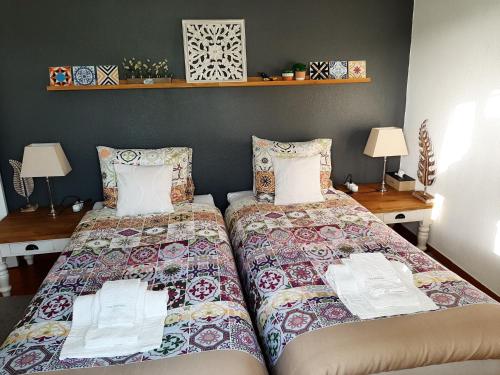 a bedroom with two beds and two tables and lamps at Casa Coloridos in Óbidos
