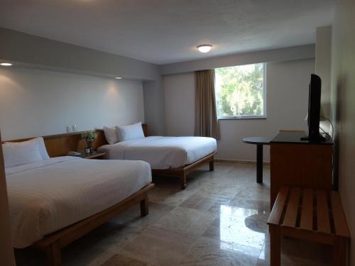 a hotel room with two beds and a flat screen tv at Hotel Amberes in Querétaro