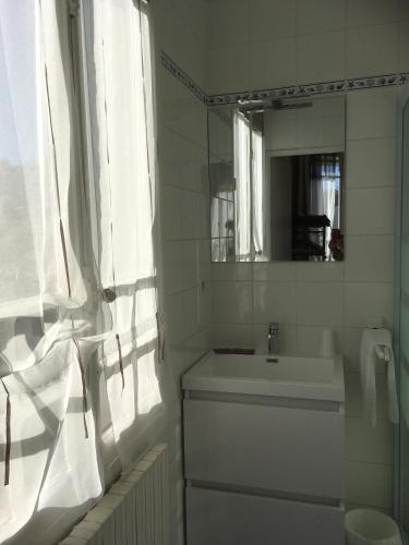 une salle de bain blanche avec un lavabo et un miroir dans l'établissement Le Narval, à Saint-Jean-de-Monts