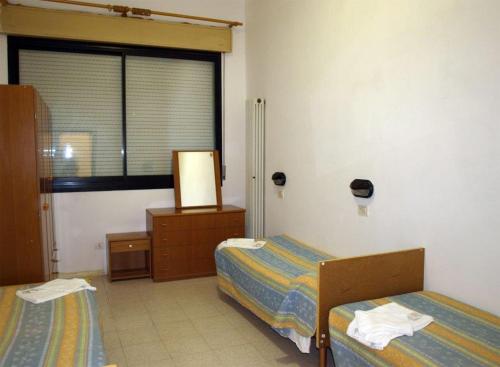 a room with two beds and a window at Villaggio Accademia in Cesenatico