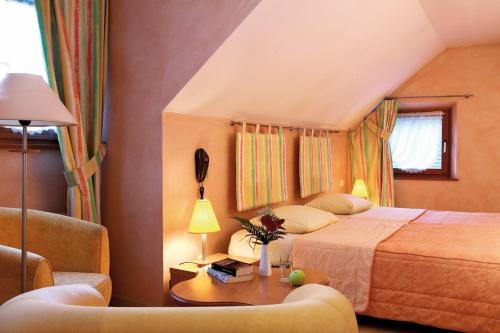 a bedroom with a bed and a couch and a table at Hôtel A la Vignette - COLMAR-NORD in Saint-Hippolyte