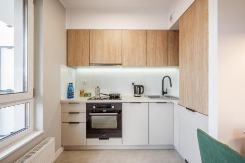 a kitchen with white cabinets and a sink at Marina Apartments ZOO in Wrocław