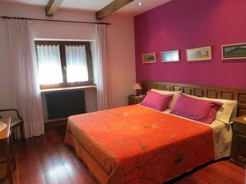 ein Schlafzimmer mit einem großen Bett mit lila Wänden in der Unterkunft Herranetxe in Bóveda