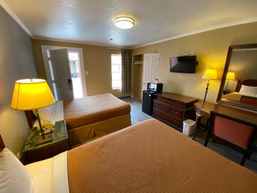 Habitación de hotel con 2 camas y escritorio en Travel Inn Snyder, en Snyder