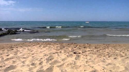 a sandy beach with waves in the ocean at Minois Boutique Hotel in Stalida