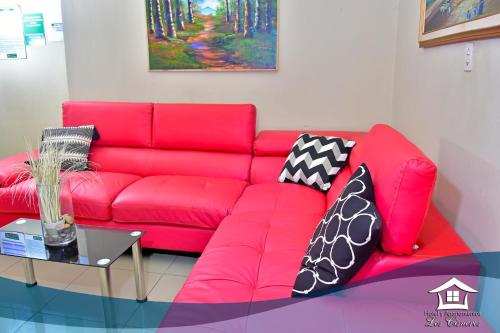 a red couch in a living room with pillows on it at Hotel y Apartments Los Cisneros in Managua