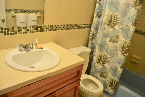 a bathroom with a sink and a toilet and a shower curtain at Waterway Condos in Nassau