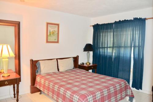 a bedroom with a bed with a plaid blanket and a window at Waterway Condos in Nassau