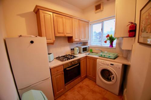 una pequeña cocina con nevera y lavavajillas en Lymm Village Apartment en Lymm