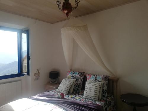 a bedroom with a bed with a canopy and a window at Parfumu Di Celu in Corte