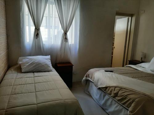 a bedroom with two beds and a window with curtains at Hostal Los Castaños in Viña del Mar