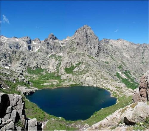 a large blue lake in the middle of a mountain at Parfumu Di Celu in Corte