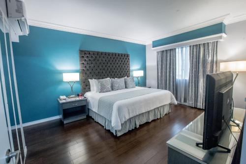 a bedroom with a bed with blue walls and a tv at Plaza de Oro in Monterrey