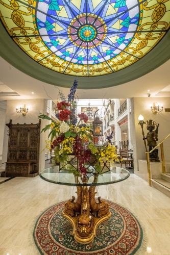 a glass table with flowers in a room with a stained glass ceiling at Plaza de Oro in Monterrey