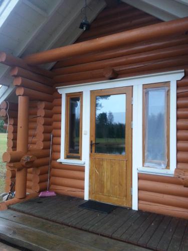 a log cabin with a wooden door and windows at Kauksi Puhkemaja in Kauksi
