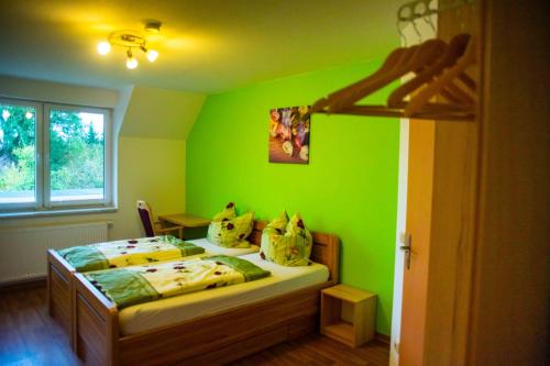ein grünes Schlafzimmer mit einem Bett in einem Zimmer in der Unterkunft Gästehaus Schulz in Schenkendöbern