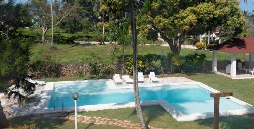 a swimming pool in a yard with chairs and trees at El Pelicano Apart-Hotel in Las Galeras