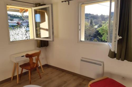 a small room with a desk and two windows at Studio dans un cadre champêtre in Mas-Saintes-Puelles