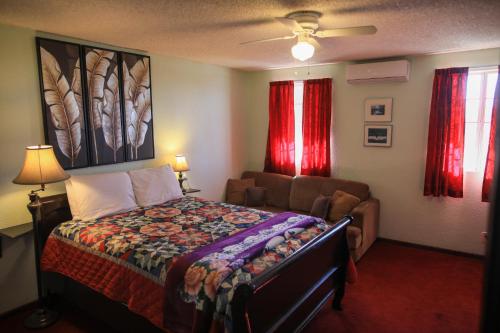 a bedroom with a bed and a couch and red curtains at Playa Hermosa Inn at the beach in Ensenada
