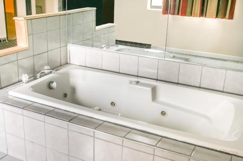 uma banheira branca na casa de banho com um espelho em Hotel 7 Inn Vienna em Vienna