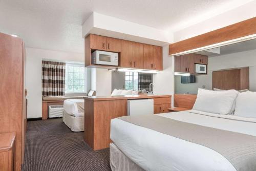 a hotel room with a large bed and a kitchen at Microtel Inn & Suites by Wyndham Rice Lake in Rice Lake