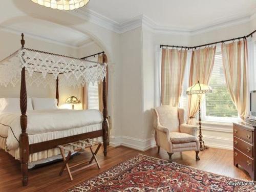 a bedroom with a canopy bed and a chair at Sojourn DuPont at The Circle in Washington, D.C.