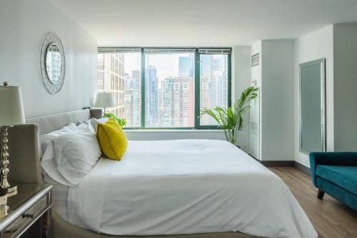 1 dormitorio con 1 cama blanca grande con almohada amarilla en ENVITAE Luxury Sky Loft Indoor Pool & Gym, en Chicago