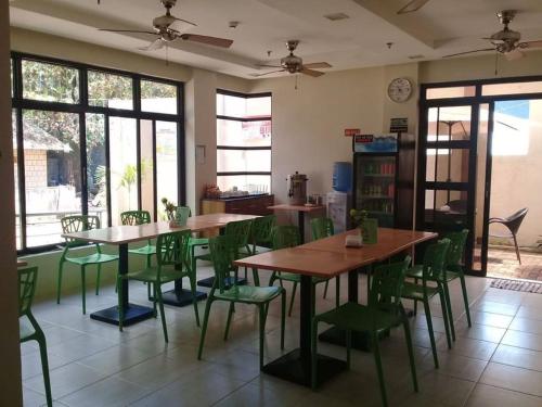 jadalnia ze stołami i zielonymi krzesłami w obiekcie Coron Visitors Hotel w mieście Coron