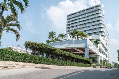 a large building with palm trees in front of it at Grand Jomtien Palace Hotel - SHA Extra Plus in Jomtien Beach