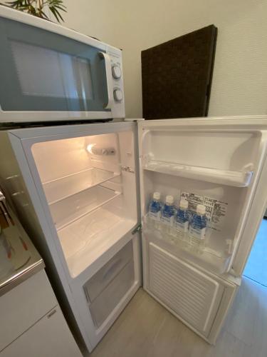 an open refrigerator with bottles of water in it at おもてなしハウスさいたま in Saitama