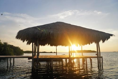 a beach with a straw umbrella in the water at Kitelantis Hotel and Resort in Kalpitiya