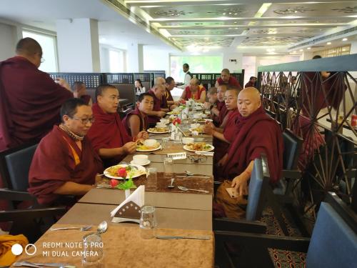 a group of monks sitting at a table eating food at Maya Heritage in Bodh Gaya