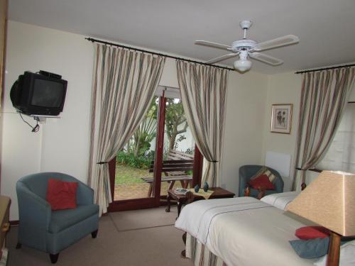 a bedroom with a bed and two chairs and a television at Melkhoutkloof Guest House in Outeniqua Strand
