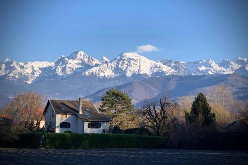 une maison avec des montagnes enneigées en arrière-plan dans l'établissement Appartement neuf scintillant de l’île d’amour, à Meylan