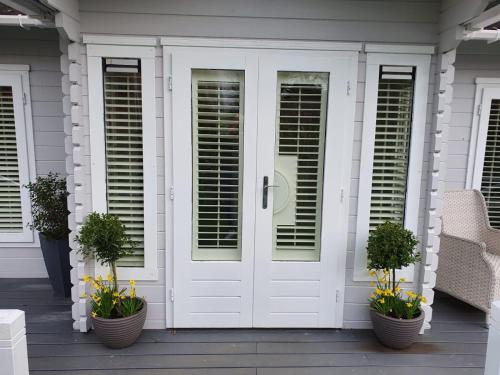 a white door on a house with potted plants at Willow House B&B in West Wittering
