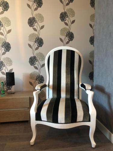 a black and white chair in a room with a wall at Maison d'hôtes La Colombelle in Colombé-le-Sec
